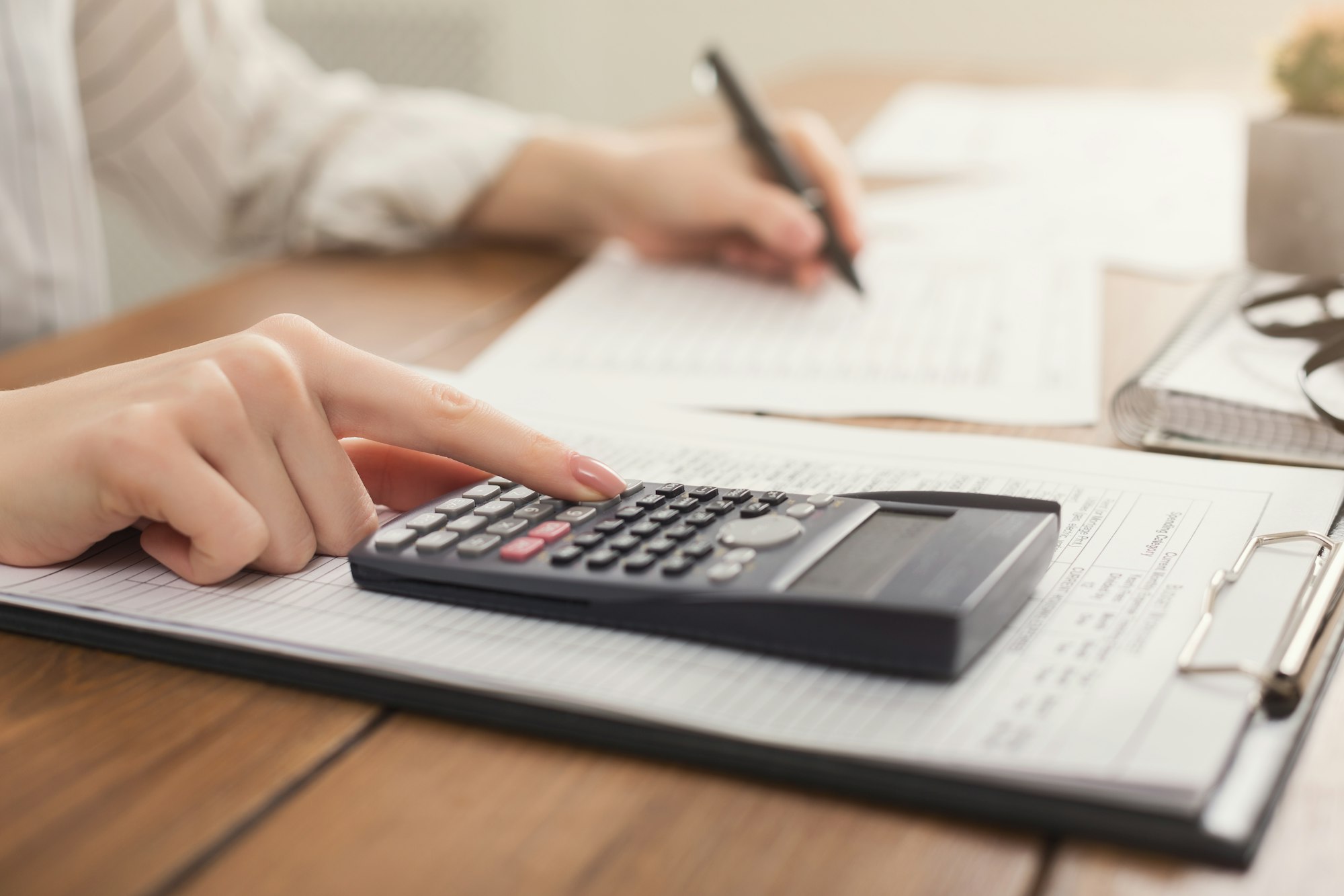 Closeup of woman hands counting on calculator